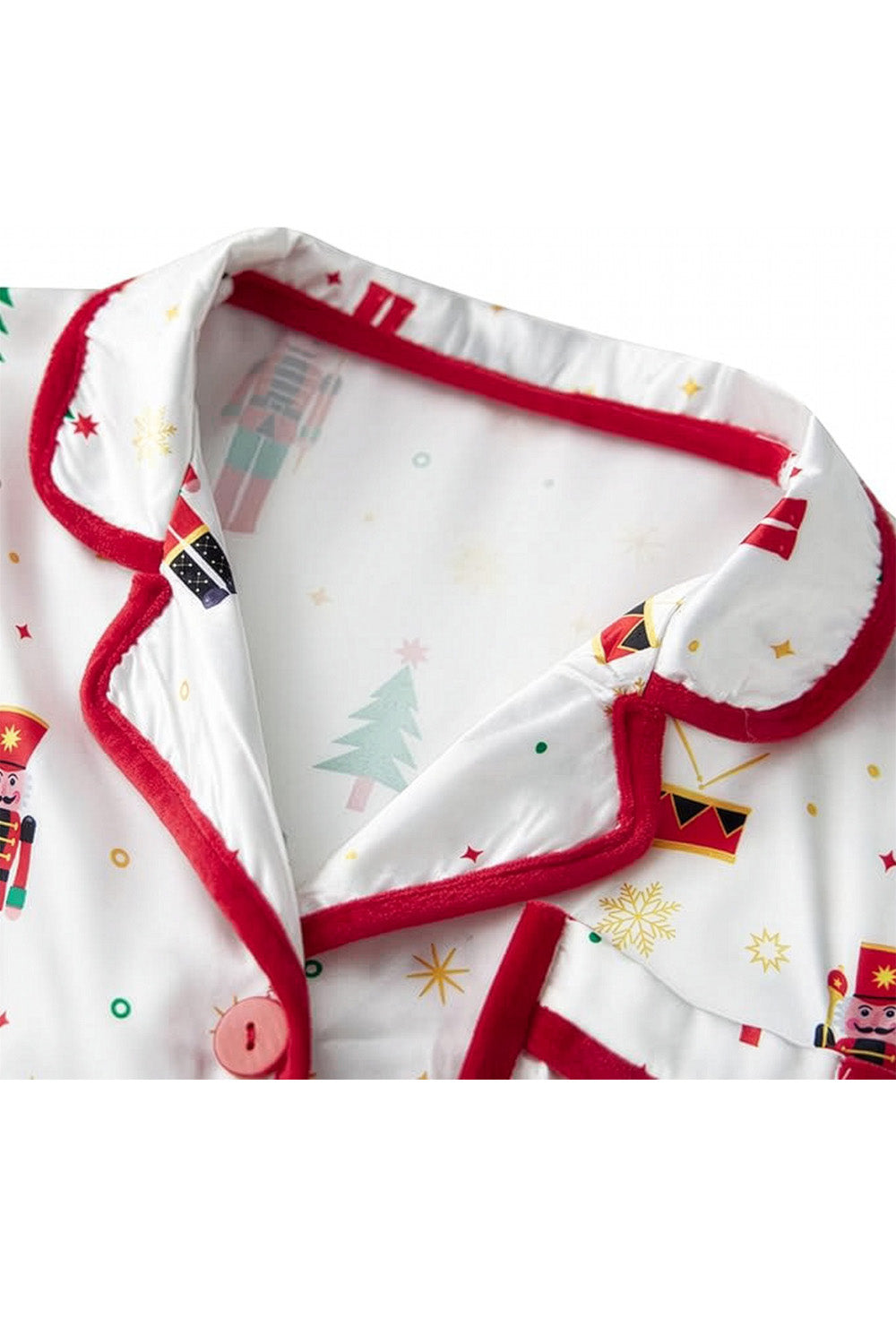 Close-up of a baby outfit with red trim and festive patterns on a white background