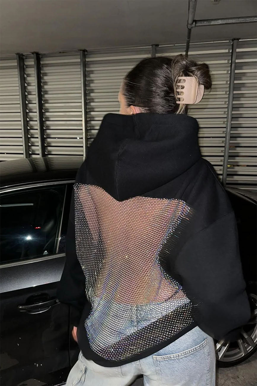 Person wearing a black jacket with a unique back design, standing in a car interior.