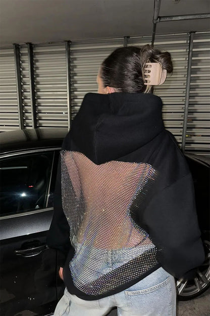 Person wearing a black jacket with a unique back design, standing in a car interior.