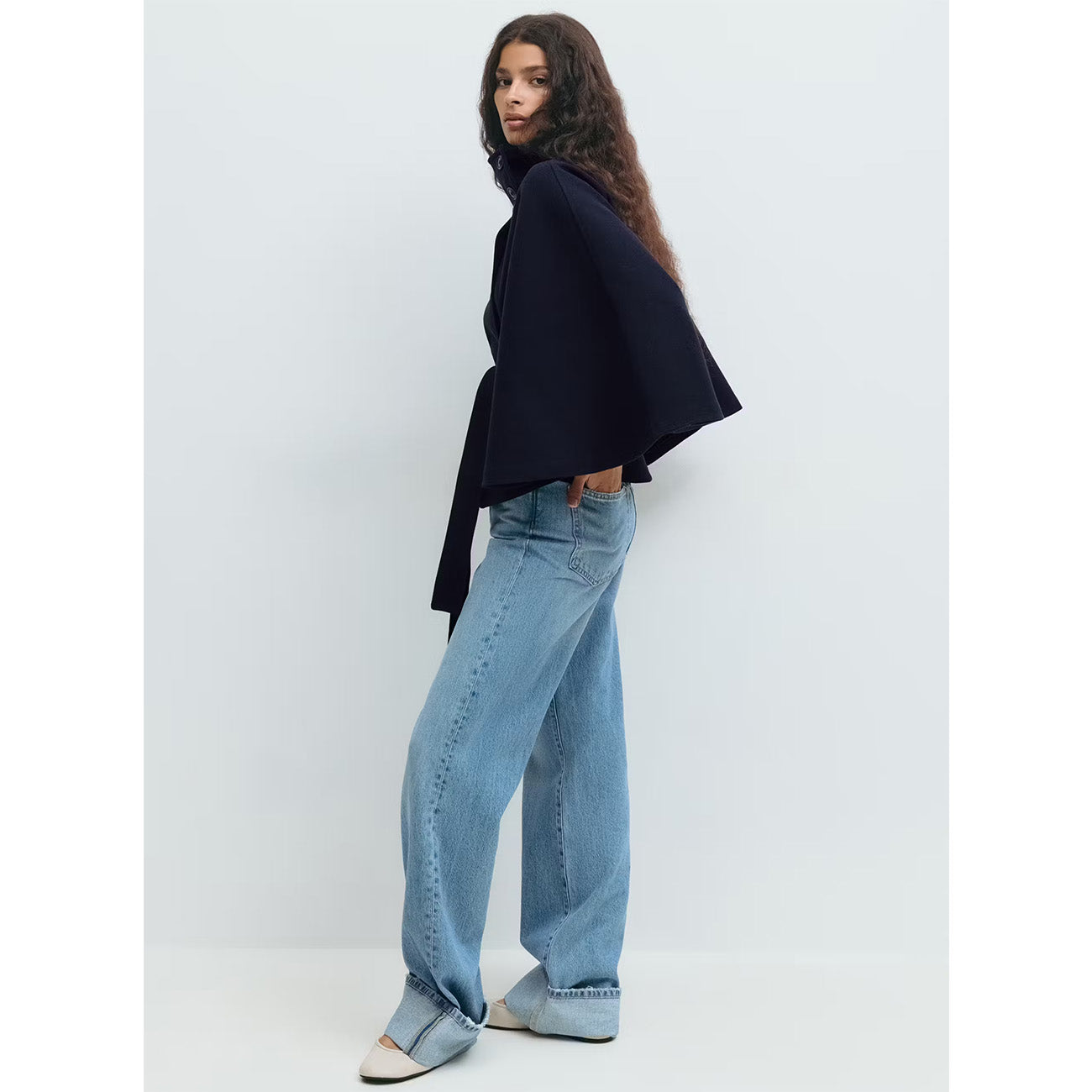 Person wearing a black top and light blue jeans against a white background