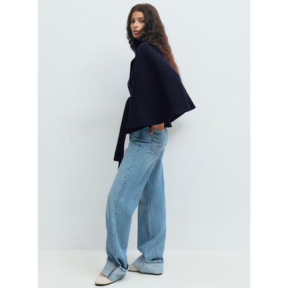 Person wearing a black top and light blue jeans against a white background