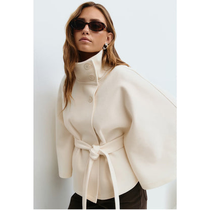 Woman wearing a cream-colored coat with a white background