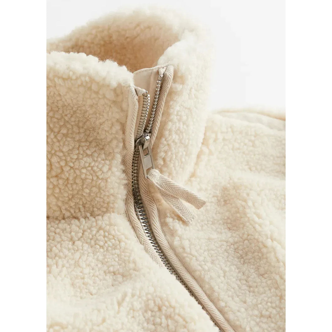 Close-up of a beige fleece jacket with a zipper on a white background