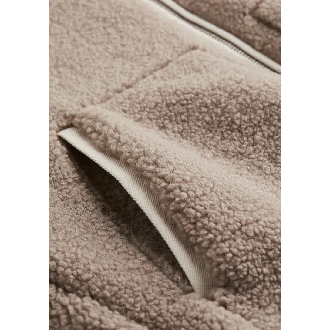 Close-up of a beige fleece fabric with a white zipper
