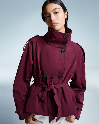 Maroon coat with black buttons worn by a model on a light gray background