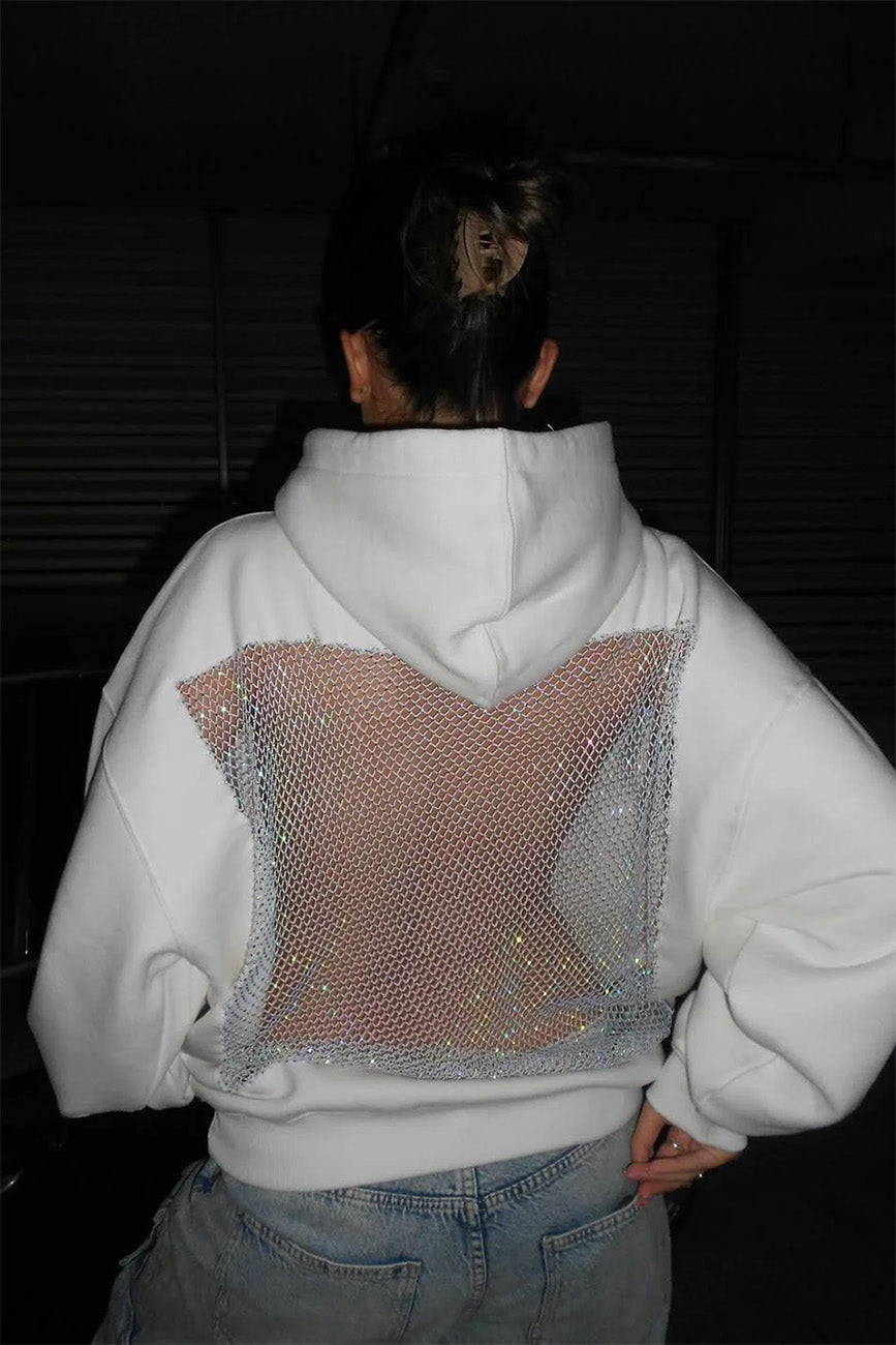 Person wearing a white hoodie with a unique back design in a dark setting